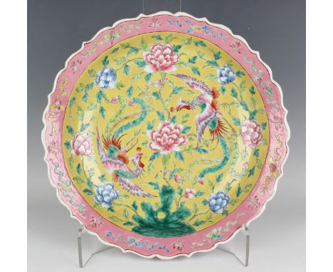 A Chinese famille rose porcelain circular dish, 20th century, painted with a pair of fenghuang flying amidst peony on a yello