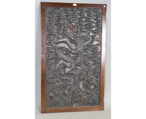 A Chinese carved hardwood rectangular panel, late Qing dynasty, decorated in relief with two dragons, flaming pearl and vapou