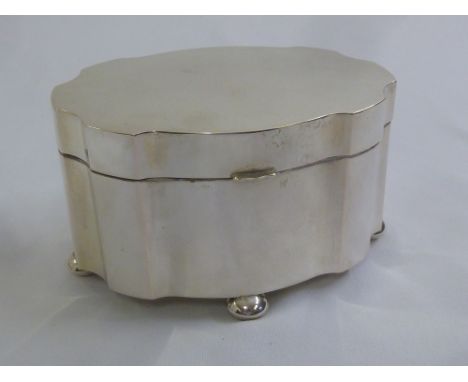 A Continental white metal shaped oval tea caddy with hinged cover on four bun feet