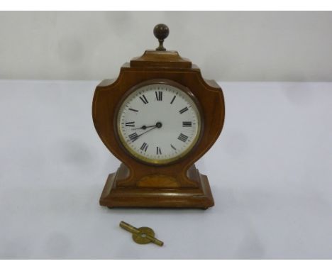 An Edwardian mahogany and inlaid satinwood mantle clock of shield form, enamel dial with Roman numerals, to include key