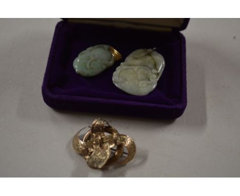 Two carved jade pendants; and a yellow metal buckle brooch 