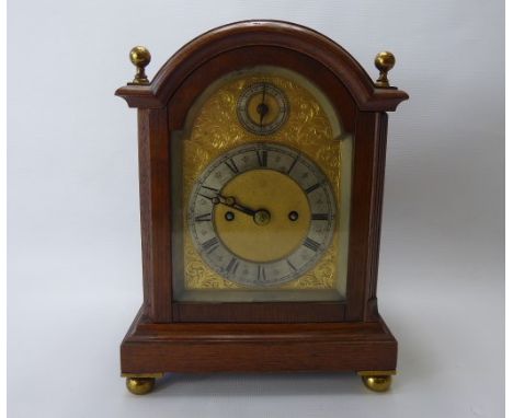 An Edwardian English Striking Bracket Clock, the clock having an oak break arch top case with brass corner finials. The finel