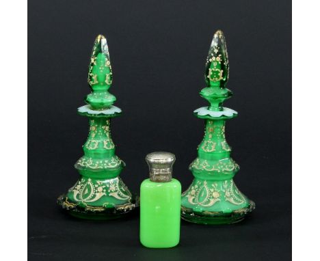 A pair of late 19th Century green glass scent bottles of octagonal tapered form with pointed stoppers, painted cream and gild