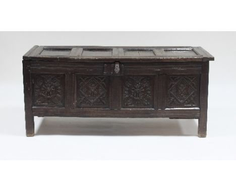 A 17th Century oak chest, the four-panel top with iron lock plate and hasp, above four carved panels, 135cm wide