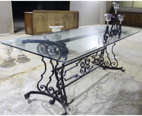 A large glass top table with a wrought iron scrolling support, mounted with a three light table light, the top 201cm x 91cm