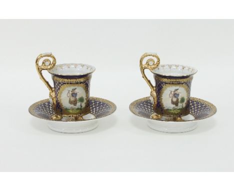 A pair of French porcelain chocolate cups and saucers each painted with two figural panels within a blue ground and gilt over
