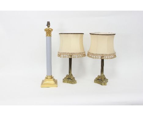 A gilt brass and plastic Corinthian column table lamp and a pair of column table lamps on three scroll feet