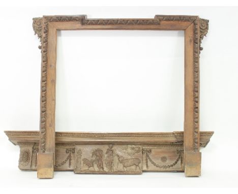 A pine chimneypiece, the frieze with central carved panel depicting a classical pastoral scene flanked by carved swags, compl