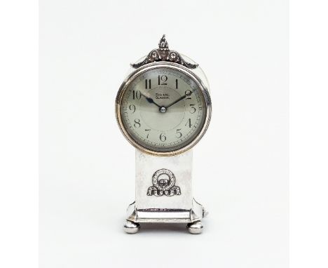 A silver mantel clock, Chester 1922, the drum shaped case with flame and scroll finial on a square plinth with wreath in low 