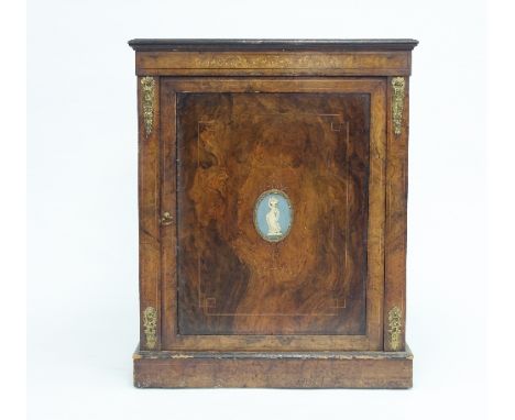 A Victorian walnut side cabinet with scroll inlaid frieze above a panelled door set with a Wedgwood panel, 82cm wide