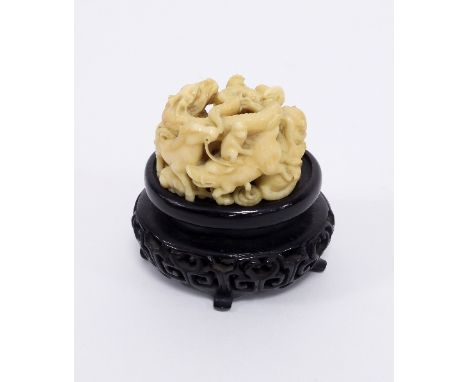 A Japanese carved ivory netsuke, Meiji period, modelled as a coiled dragon above a surround of pig, tiger, goats, cockerel, h