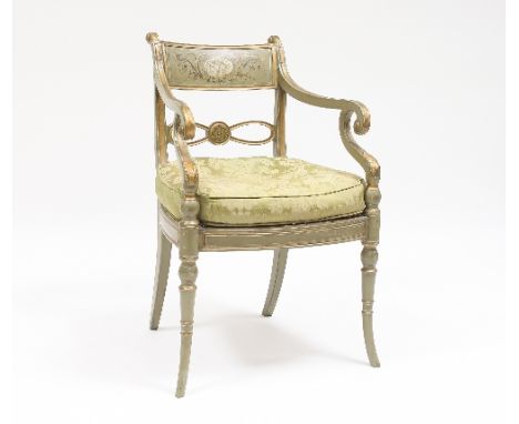 A Regency parcel gilt and green armchair, painted a cherub panel within leaf scrolls, with scroll arms and turned tapering le