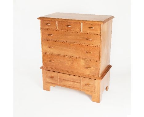 A walnut chest on stand by Bert Uzzell, the rectangular top with moulded border and fitted three long and three short drawers