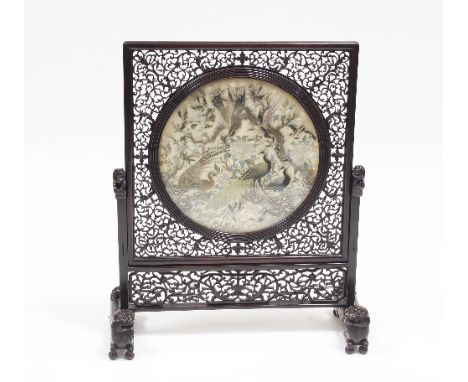 A Chinese pierced hardwood screen set a circular needlework panel of exotic birds within flowering branches, the support capp