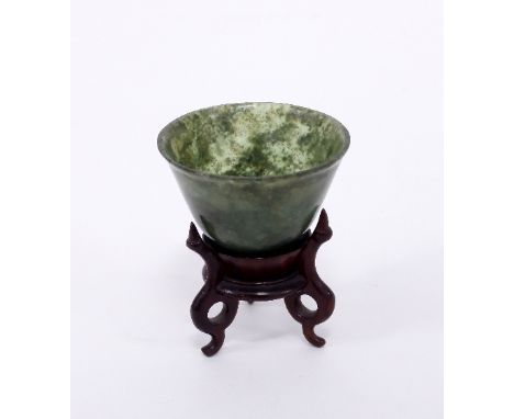 A small green jade/nephrite bowl, 5.5cm diameter, on a wooden stand