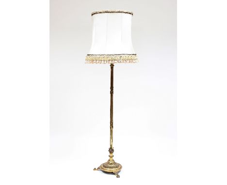 A brass standard lamp, the ribbon-tied reeded column on circular base and lion paw feet, 132cm high