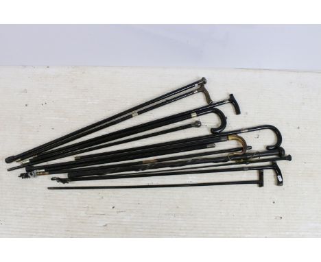 Assorted ebonised wood walking stick canes with silver and horn handle examples and a riding crop