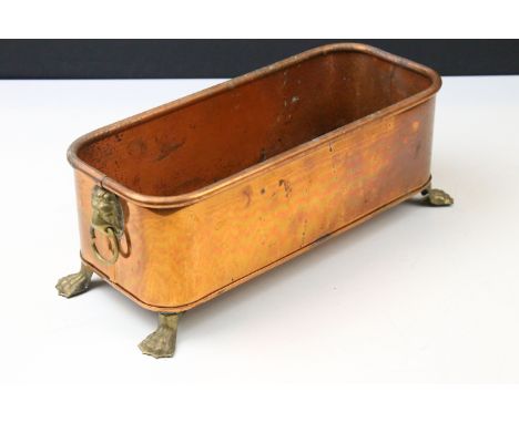 Small copper planter having twin lion mask handles and lions paw feet. Measures 29cm wide.
