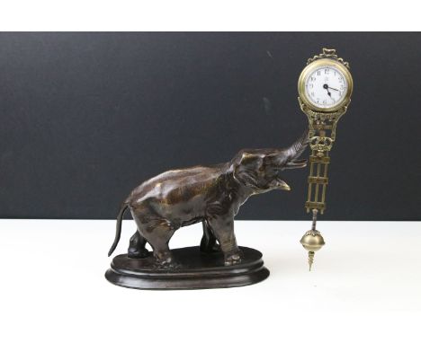 Novelty elephant clock having a cast metal elephant on wooden base with swinging clock to the raised trunk. Dial marked J. Me
