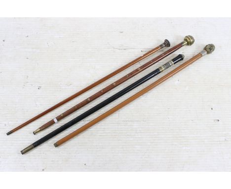 Group of four wooden walking stick canes with varying handles to include a brass four faces example, lion's face topped stick