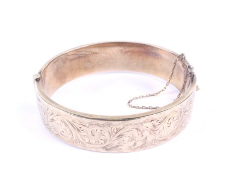 A vintage 9ct gold hollow hinged bangle. The broad D-section hoops part foliate engraved, hallmarks for Birmingham 1973, 16mm