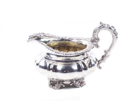 A George IV silver milk jug by Paul Storr  Shaped-round or melon-fluted and engraved with a cartouche and with an applied she