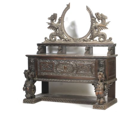An oak heavily carved sideboard.the top section sitting on carved winged dragons,central drop flap door.upper shelf raised on