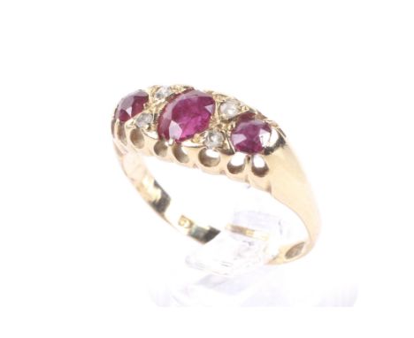 An Edwardian gold, ruby and diamond dress ring. The three graduated oval and cushion-shaped mixed-cut rubies spaced by pairs 