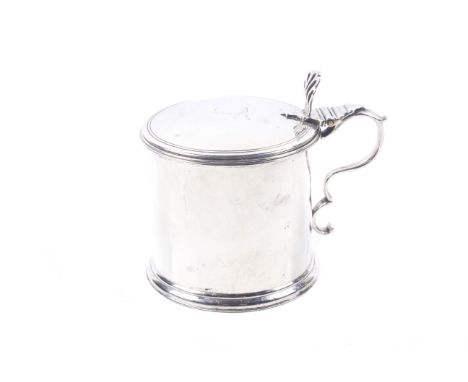A George III silver drum shaped mustard pot. with moulded borders and a double-scroll handle, the hinged lid with a pierced t