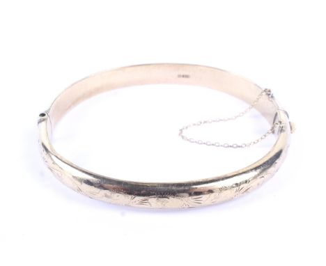 A vintage 9ct gold part foliate engraved hollow hinged bangle. Hallmarks for Birmingham 1965, 7.7mm wide, 10g
