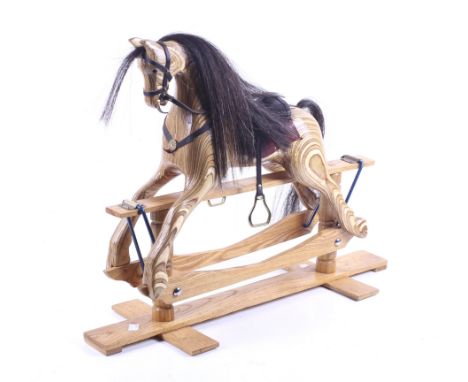 A 20th century model of a rocking horse.Oak base to a carved plywood body.Horse hair tail and maine,leather saddle and reins.