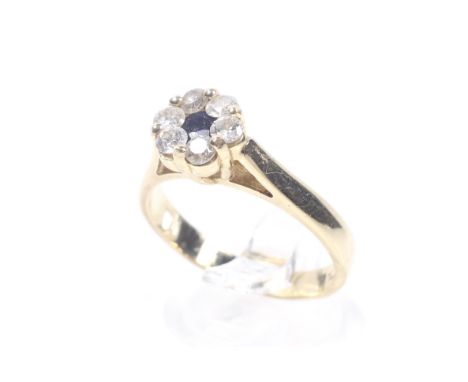 A vintage sapphire and diamond cluster ring. Centred with a small round mixed-cut sapphire within a diamond six stone border,