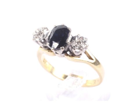 A vintage 18ct gold, sapphire and diamond three stone ring. Centred with an oval mixed-cut very-dark-blue/black sapphire, bet