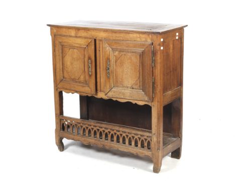 An 18/19th century French wooden two door sideboard. Of peg jointed construction, with a pair of panelled doors over a shelf 
