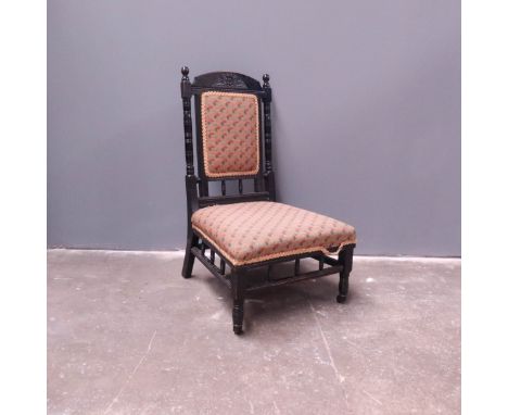 An Aesthetic Movement ebonised fireside chair, circa 1880, arched top rail with carved sunflower lunette frieze, ring turned 