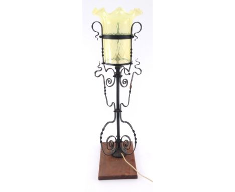 An Arts &amp; Crafts wrought iron uplighter, circa 1895, the scrollwork frame supporting a vaseline glass light shade with wa