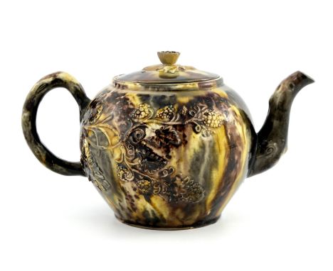 A Staffordshire teapot of Whieldon type, circa 1765, of ovoid form with flower head finial and moulded vine design, simulated