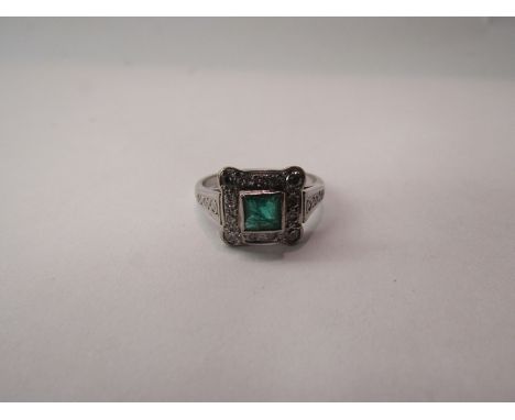 An emerald and diamond dress ring the centre emerald flanked by diamonds, shank unmarked 