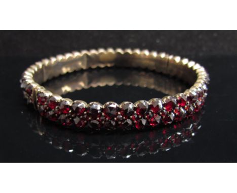 A Georgian stiff hinge bangle set with red stones (one loose)