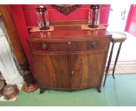 An Edwardian mahogany bow front cabinet, the single drawer over two door cupboard on outswept bracket feet with two working k