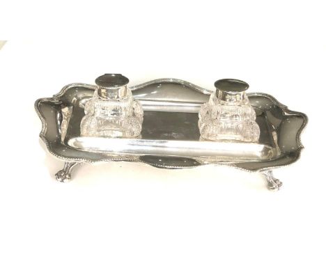 A George V silver shaped rectangular inkstand and  pair of glass inkwells with dished pen rests, beaded border lion paw feet 