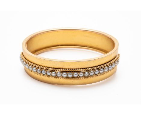 A VICTORIAN GOLD AND HALF PEARL OVAL HINGE BANGLEWith pearls mounted to the centre of half the bangle and further decorated w