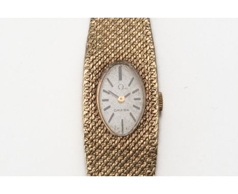 A LADY'S GOLD OMEGA WATCHWith a silver oval signed face and baton hour markers, on a woven graduating strap with fold over cl