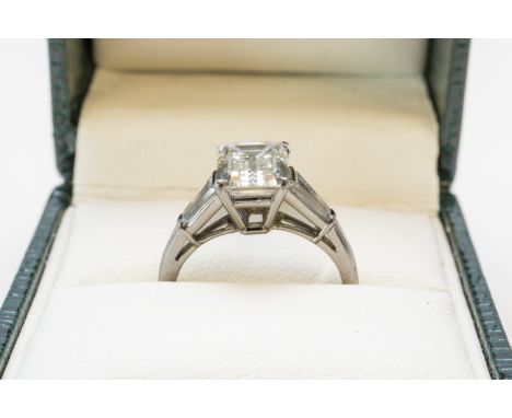 A DIAMOND THREE STONE RING (2)The central claw set emerald cut diamond weighing an estimated 2.10 carats, with an estimated c