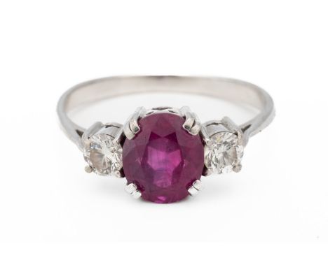A RUBY AND DIAMOND THREE STONE RINGWith a central oval cut ruby flanked either side by a round brilliant cut diamond, all cla
