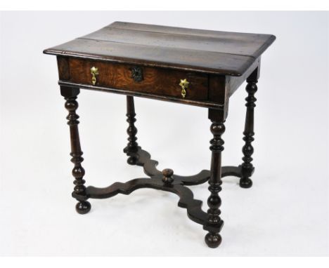 A part early 18th century oak side table, the bevelled rectangular planked top above a frieze drawer with brass pear drop han