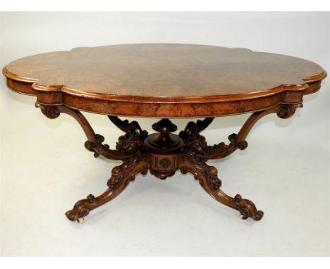 A Victorian figured walnut centre table circa 1860 the shaped and bevelled figured quarter veneered oval top raised on four o