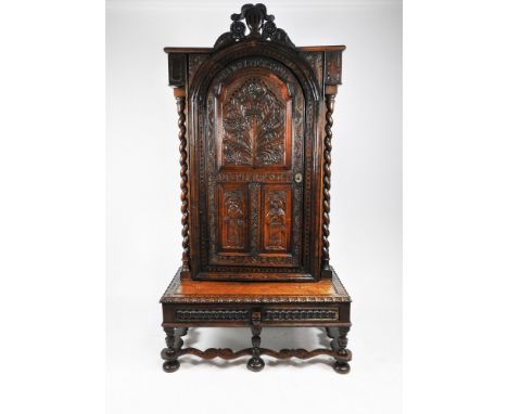 A Victorian carved oak bookcase cabinet on stand, 19th century, in Carolean style, surmounted by a carved knight's helm and p