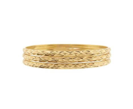 Three high carat gold engraved bangle bracelets, Egyptian marks, inner diameters 6.4cm, 26.2gOverall good conditionLight to m