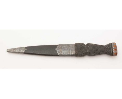 A Sgian Dubh, the 9cms stainless steel blade on a carved horn hilt of knot design and set an orange paste stone, the hilt and